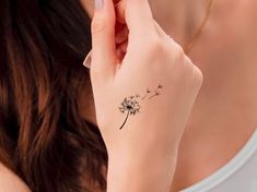 a woman's wrist with a dandelion tattoo on her left hand and the back of her arm