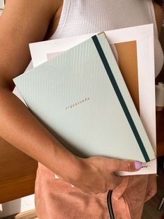 a woman holding three folders in her hands