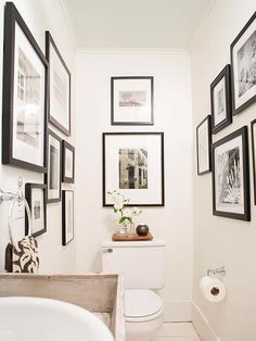 a white bathroom with black and white pictures on the wall