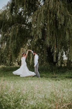 a bride and groom dancing in front of a tree