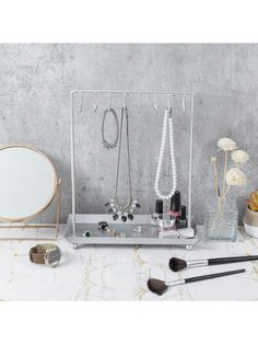 an assortment of jewelry is displayed on a table with a mirror and other items in front of it