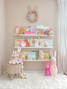 a white shelf filled with lots of books next to a pink bunny and other toys