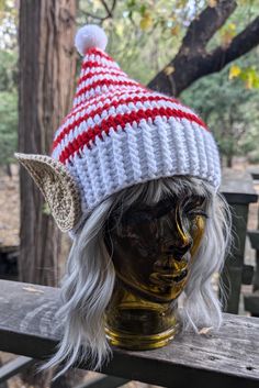 a white and red knitted hat sitting on top of a mannequin head