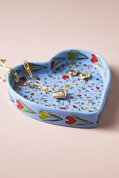 a blue heart shaped box with flowers and hearts on the inside is attached to a gold chain