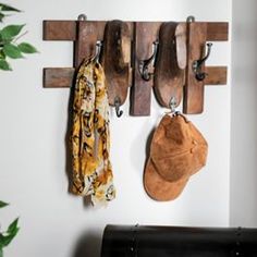 the coat rack has two hats on it and three coats hanging from hooks, along with other items