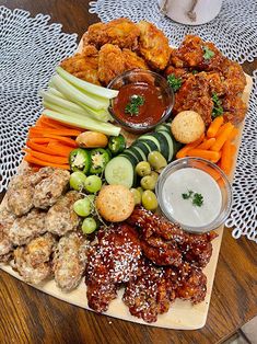 a platter with chicken wings, carrots, celery, cucumbers and other foods