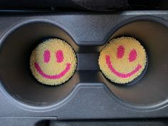 two cupcakes that have been decorated to look like smiley faces in a muffin tin