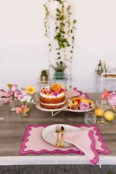 the table is set with pink and white plates, silverware, and flowers on it