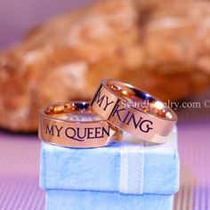 two wedding rings with the words my king and my queen on them sitting next to a piece of bread