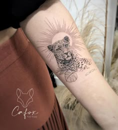 a woman's arm with a tattoo on it and a cheetah in the background