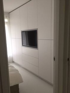 a bedroom with white walls and a flat screen tv mounted to the side of the wall