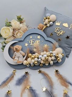 a teddy bear sitting on top of a cloud next to some feathers and flowers in front of a pillow