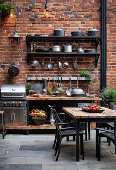 an outdoor kitchen with pots and pans hanging from the brick wall, surrounded by potted plants