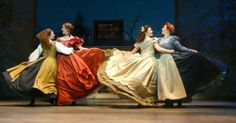 four women in dresses are sitting on a bench with their backs turned to the side