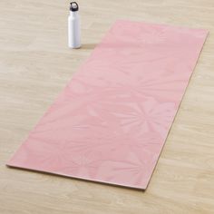 a pink yoga mat with a water bottle on the floor next to it and a white sprayer