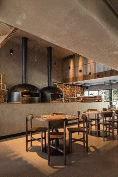 a restaurant with wooden tables and chairs in front of an open fire place on the wall