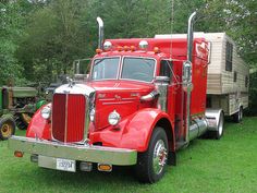 an old red truck is parked in the grass