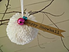 a happy snowball ornament hanging from a tree branch with a sign that says happy snowball