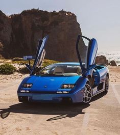 a blue sports car parked on the beach with its doors open and it's door opened