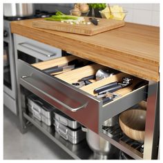 an open drawer in a kitchen with utensils and cutting board on the counter