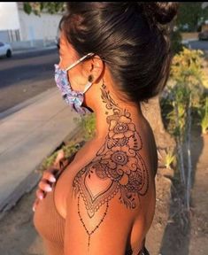 a woman with a tattoo on her back and neck is wearing a face mask to protect herself from the sun