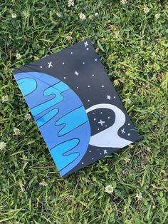 a piece of paper that is laying on the ground in the grass with space painted on it