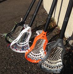 four lacrosse goalies lined up against a wall