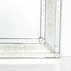 an ornate white framed mirror on the wall