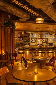 the interior of a restaurant with wooden tables, chairs and bookshelves in it