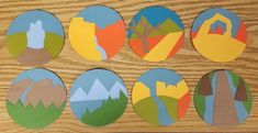 paper cut out of different shapes and sizes on a wooden surface with trees, mountains, and buildings