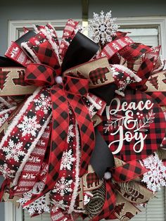 a red and black christmas wreath with the words peace joy on it hanging from a door