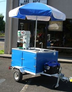 a blue and white cart sitting in front of a building with an umbrella over it