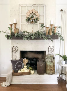 a fireplace decorated with greenery, candles and other items for the fall mantel