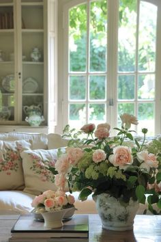 a vase filled with pink flowers sitting on top of a table next to a window