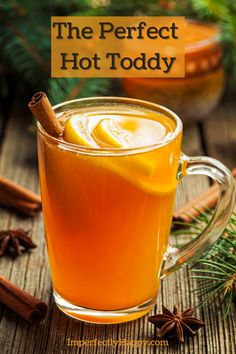 the perfect hot toddy in a glass mug with cinnamon and an orange slice on top