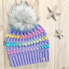 a knitted hat with a pom - pom sits next to starfish