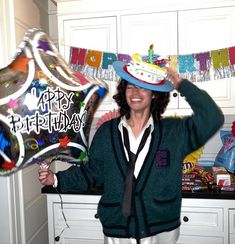 a woman wearing a birthday hat and holding up a happy birthday sign in front of her head