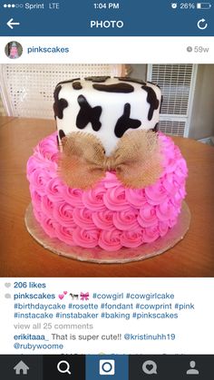 a cake decorated with pink icing and a cow print on top is sitting on a table