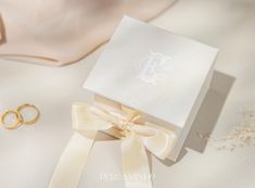 an open box with two wedding rings and a pair of earrings on top of it