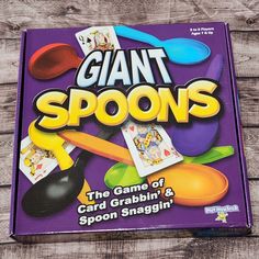 the game of giant spoons is sitting on top of a wooden table next to some scissors