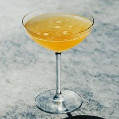 a glass filled with yellow liquid sitting on top of a white counter next to a black object