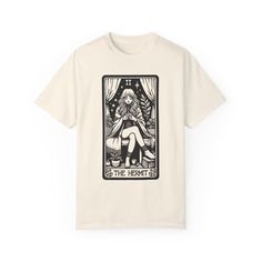 Dive into the mystique with our 'The Hermit' Black and White Tarot Card Short Sleeve Tee from Goth Cloth. This enchanting t-shirt features a captivating tarot card design of a cozy girl wrapped in a blanket, sipping tea, and reading a book. Key Features: Material: 100% Airlume combed and ring-spun cotton (4.2 oz/yd²), lightweight and breathable. Fit: Retail fit with a crew neckline, ideal for casual and semi-formal settings. Comfort: Tear-away label for reduced skin irritation with buttery soft fabric. Sustainability: Manufactured in a humane, no-sweat-shop, and sustainable way. Versatility: Great for layering or wearing on its own, suitable for both active and leisure wear. Eco-Friendly: The majority of our items are made-to-order, reducing environmentally harmful fashion waste and allowi Tea And Reading, Fashion Waste, Tarot Card Design, The Hermit, Bag Patches, Sipping Tea, Goth Clothing, Skin Irritation, Dad Caps