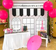 a pink umbrella sitting next to a table with cakes and balloons on top of it