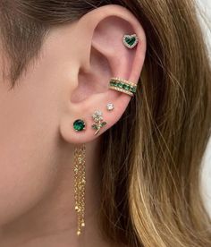 a close up of a person wearing ear cuffs with green and white stones on them