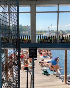 several people are sitting on the dock with beer bottles in front of them and one person is bending over