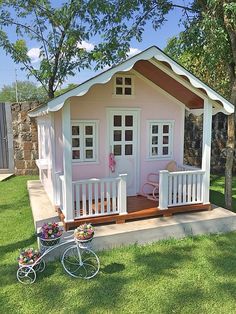 a small pink and white house on the grass with a bicycle parked in front of it