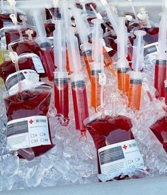 bottles filled with red liquid sitting on top of an ice covered table next to each other