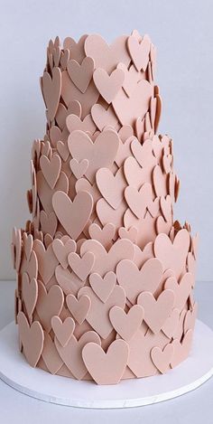 a three tiered pink cake with hearts on it