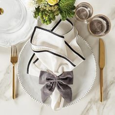 a table setting with napkins, silverware and flowers on the plate next to it