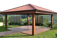 a wooden gazebo sitting on top of a lush green field